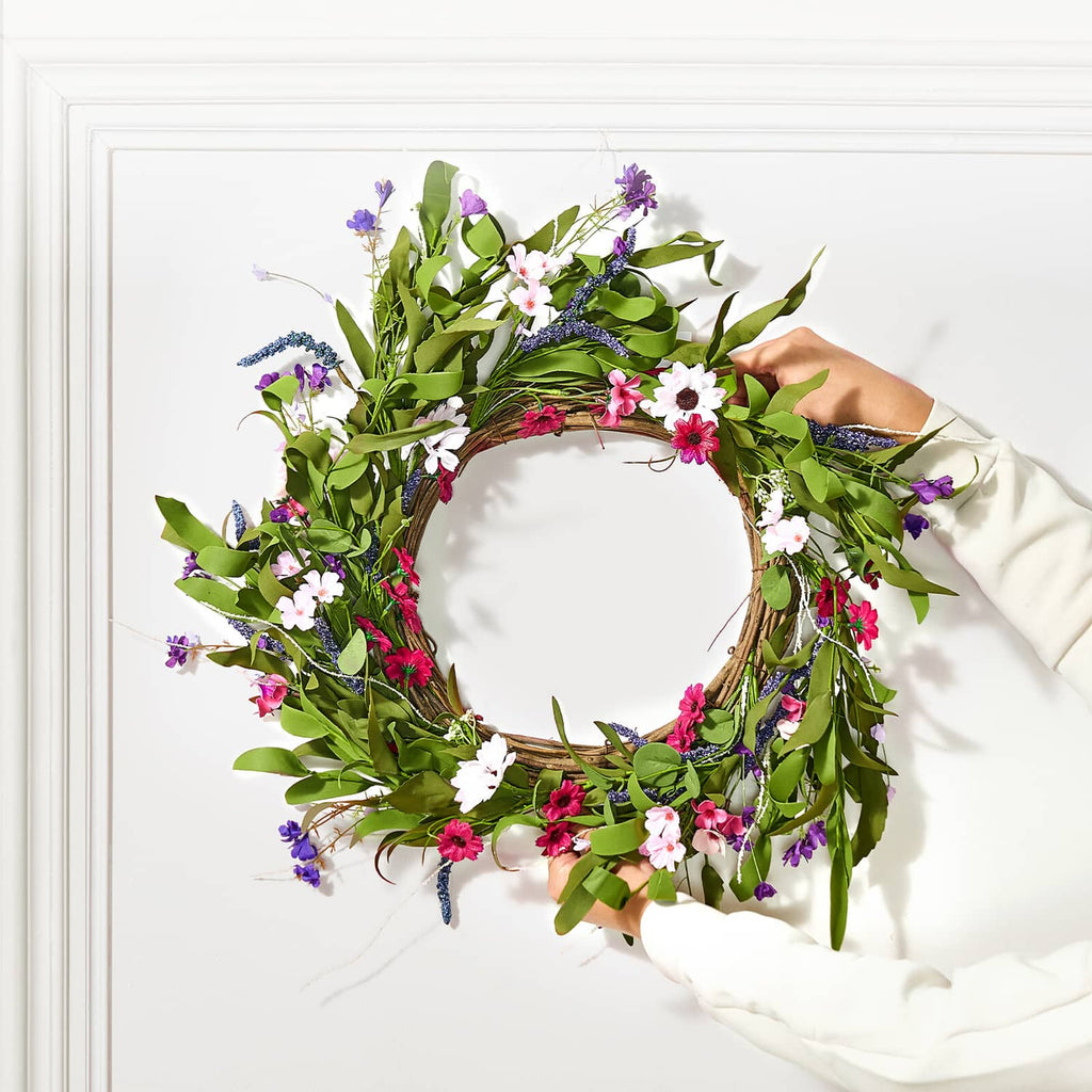Hanging artificial wreath with green leaves, pink flowers, and purple blossoms on ring