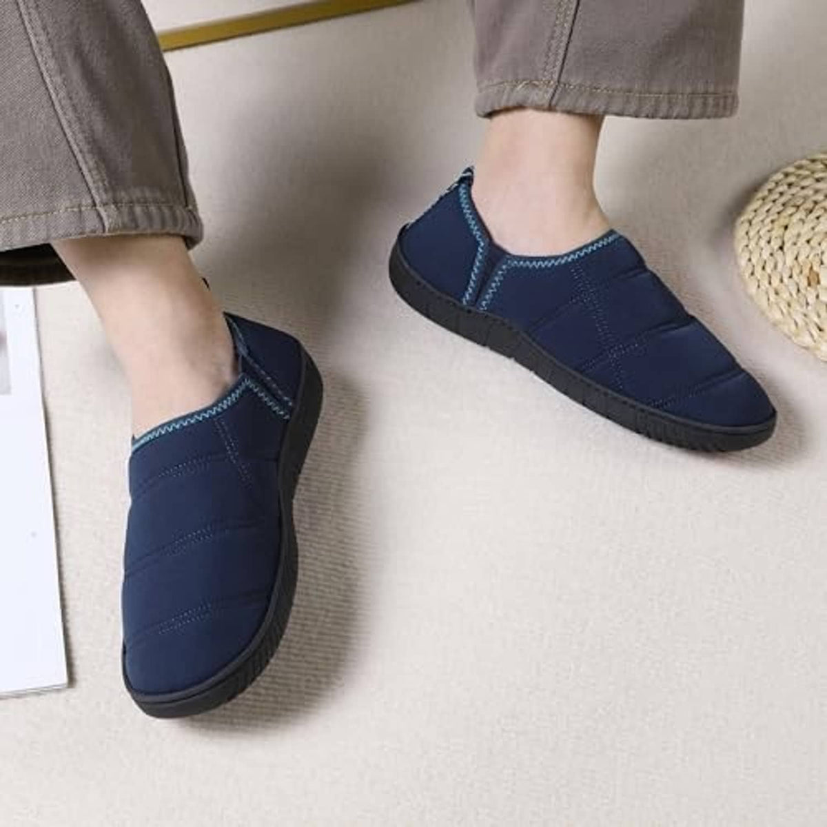 Pair of blue slip-on slippers worn with casual pants and closed-toe design