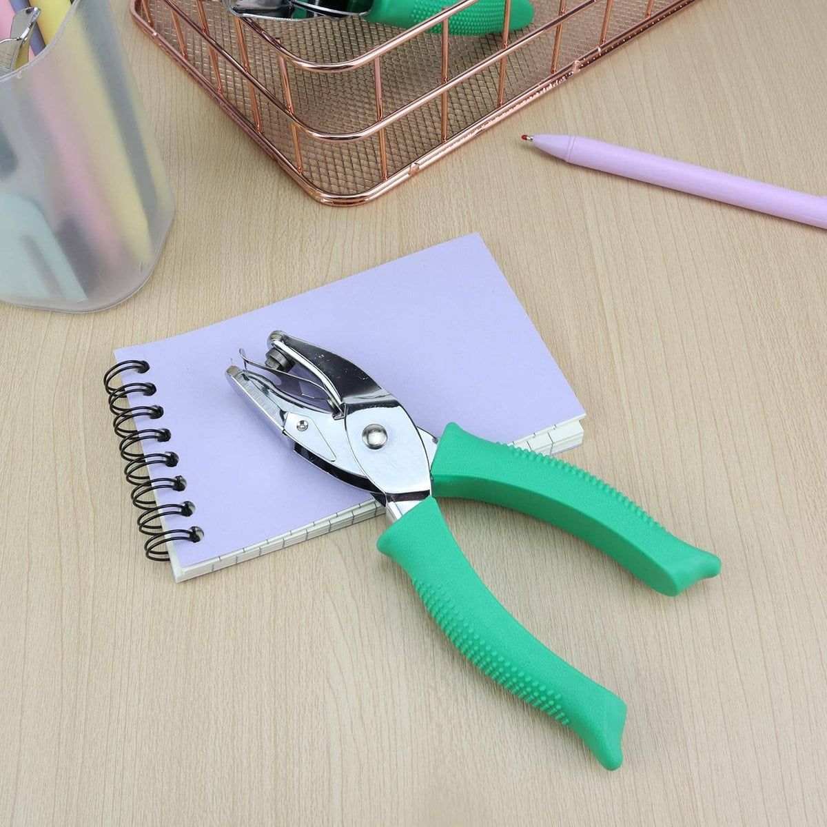 Handheld triangle hole punch with green handles for punching paper sheets