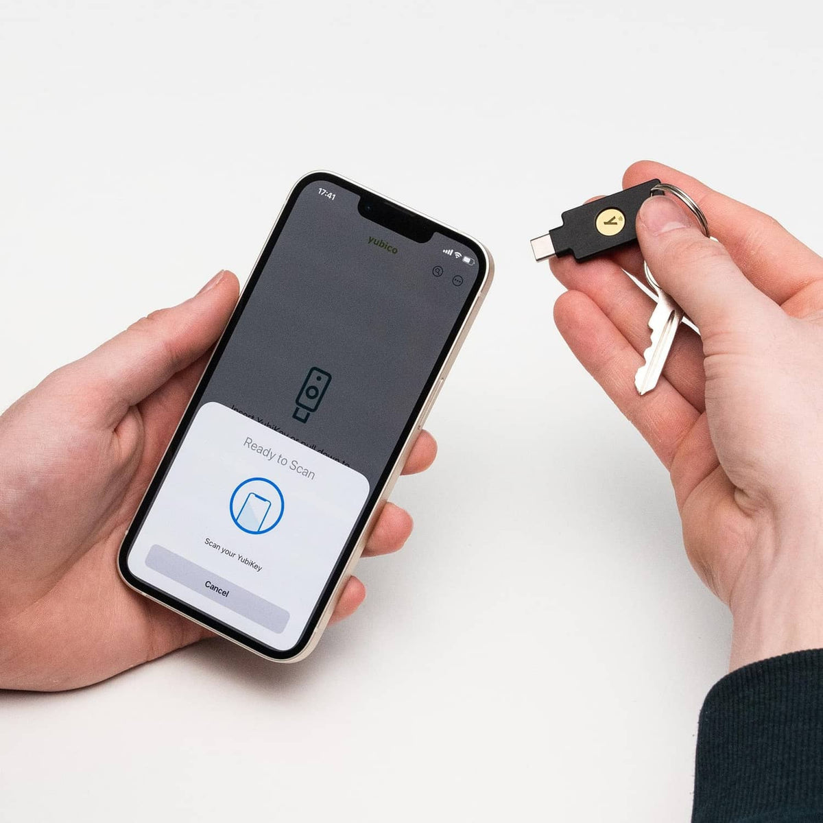 Hands using a black NFC USB-C security key with a phone authentication screen