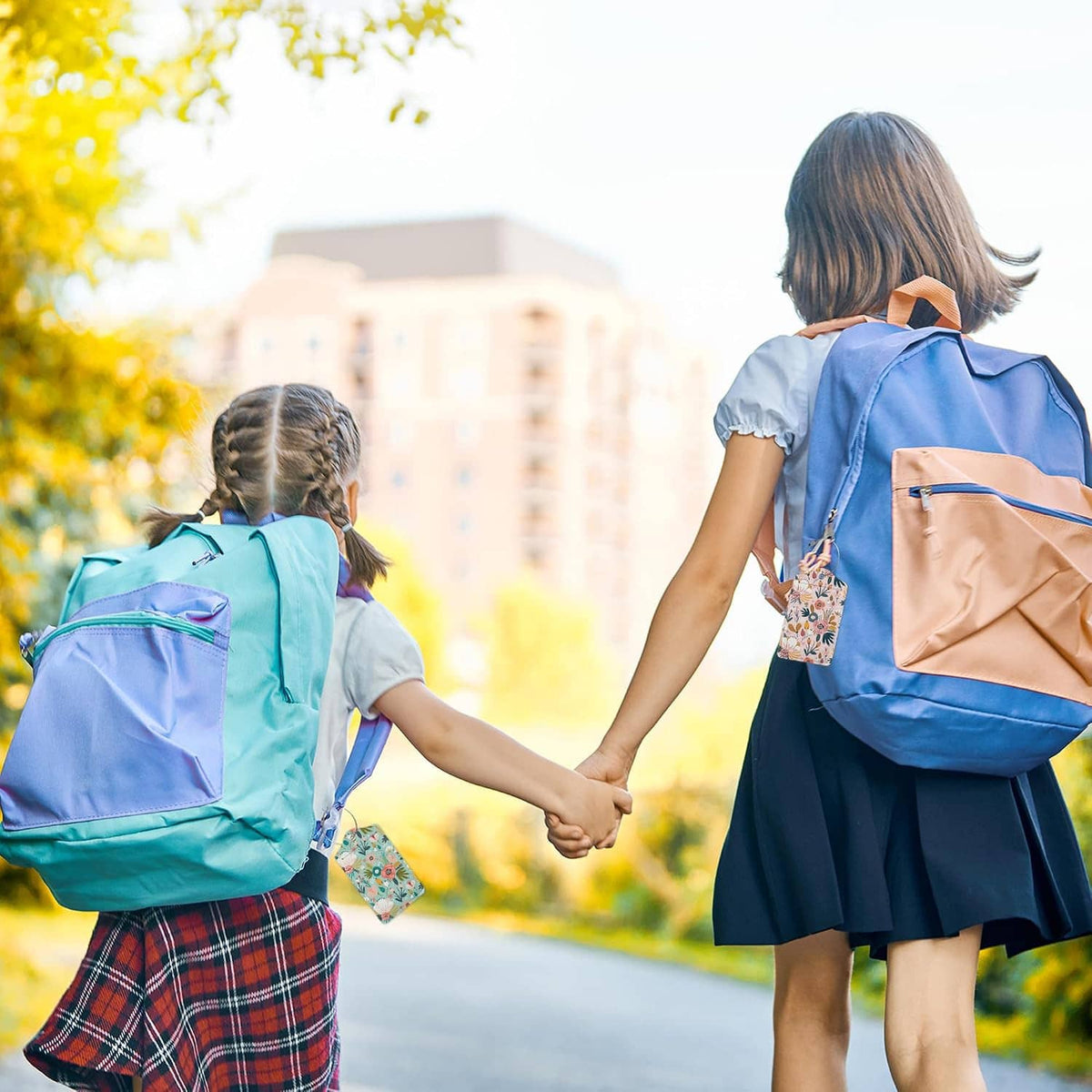 Floral luggage tag attached to a school backpack with metal ring and braided cord