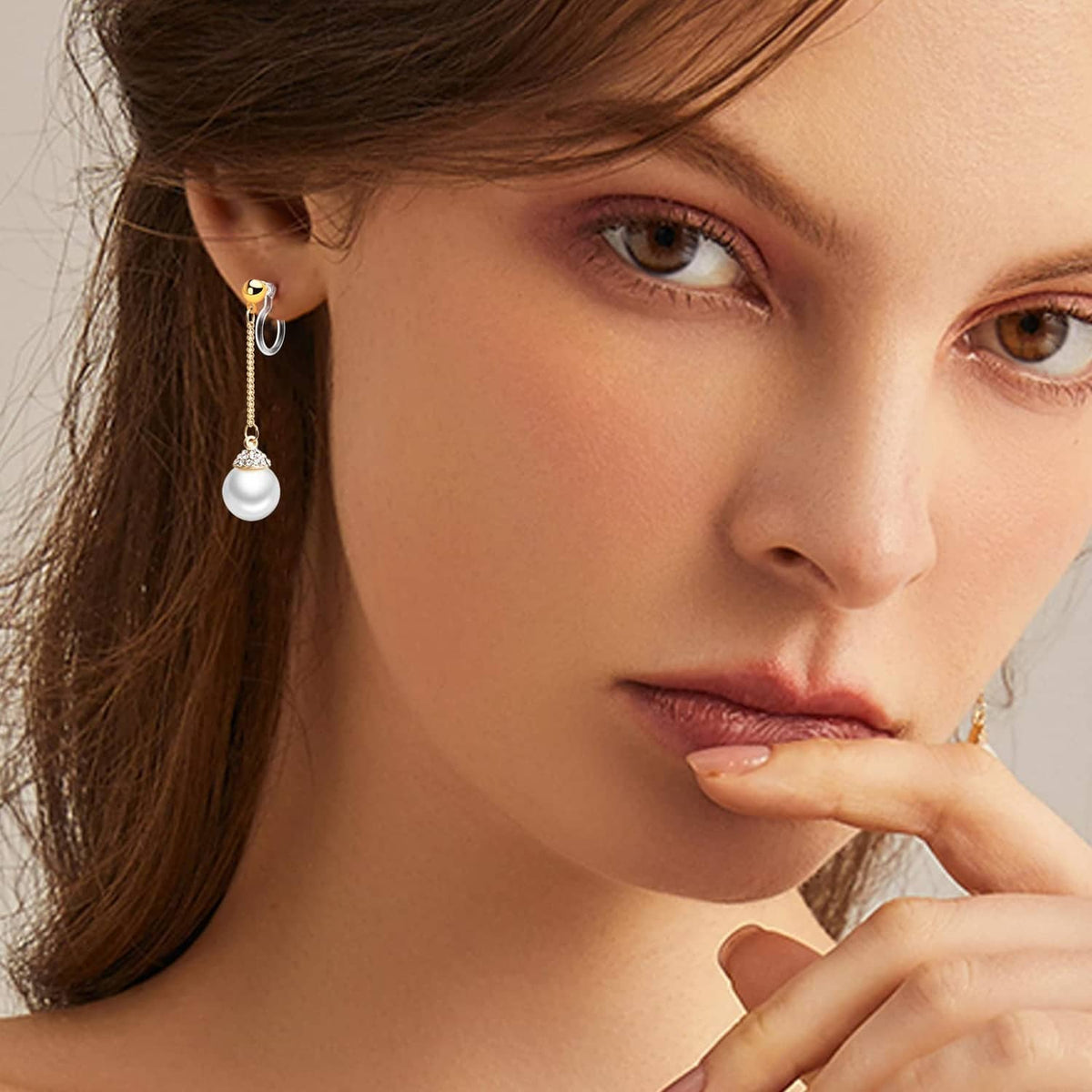 Pearl drop clip-on earring with gold-tone hoop and clear hook, worn on ear