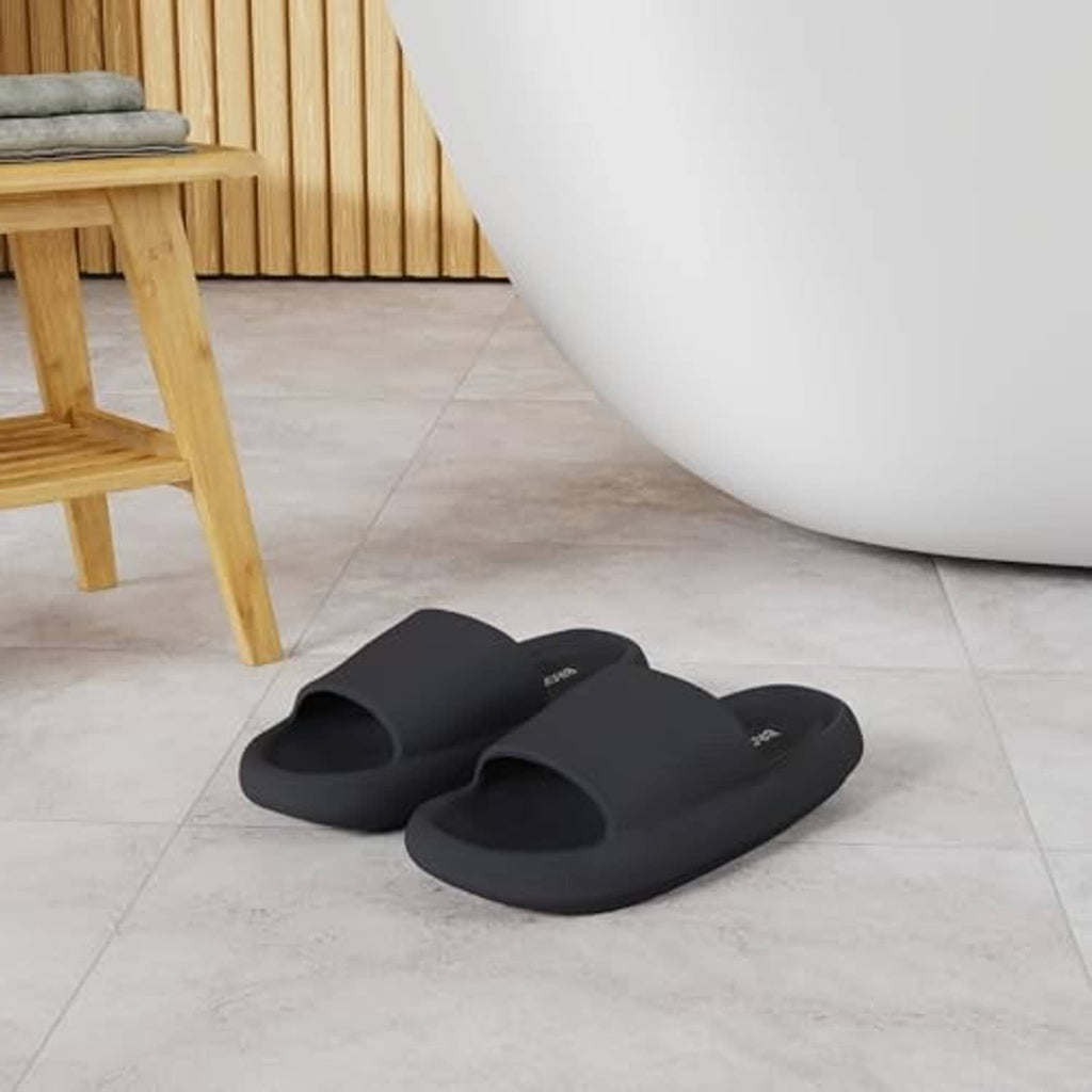 Pair of black pillow slippers with open toe and wide strap, shown side by side.