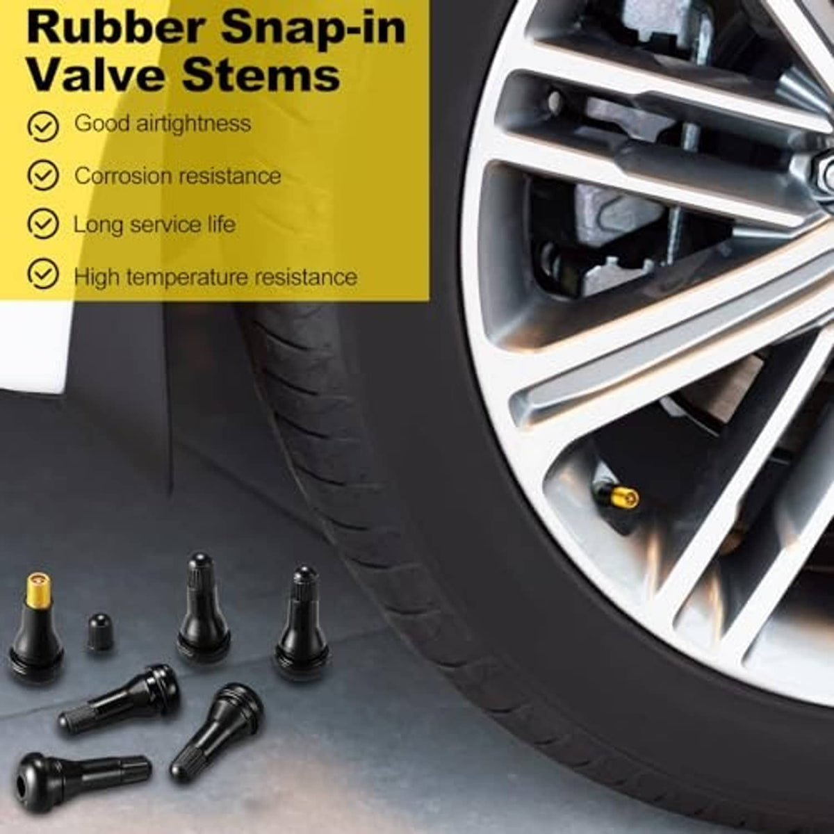 Black rubber snap-in valve stems near a car wheel, with brass valve cores