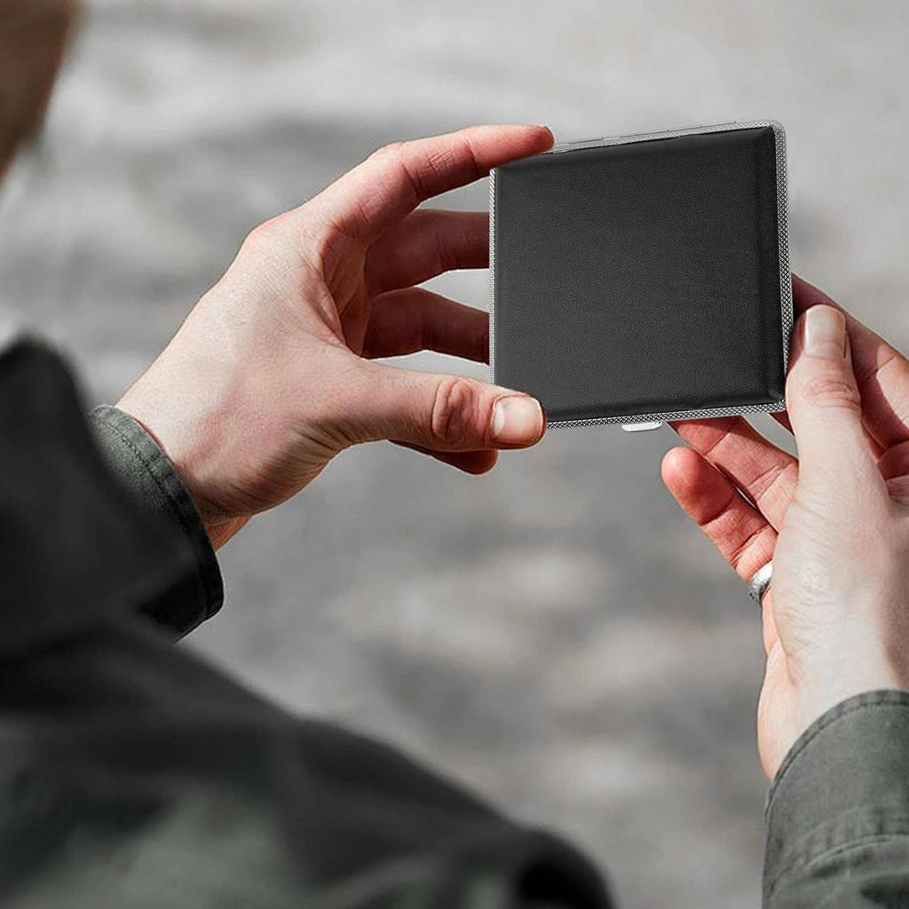 Black slim cigarette case held in hands, thin leather cover with silver textured trim