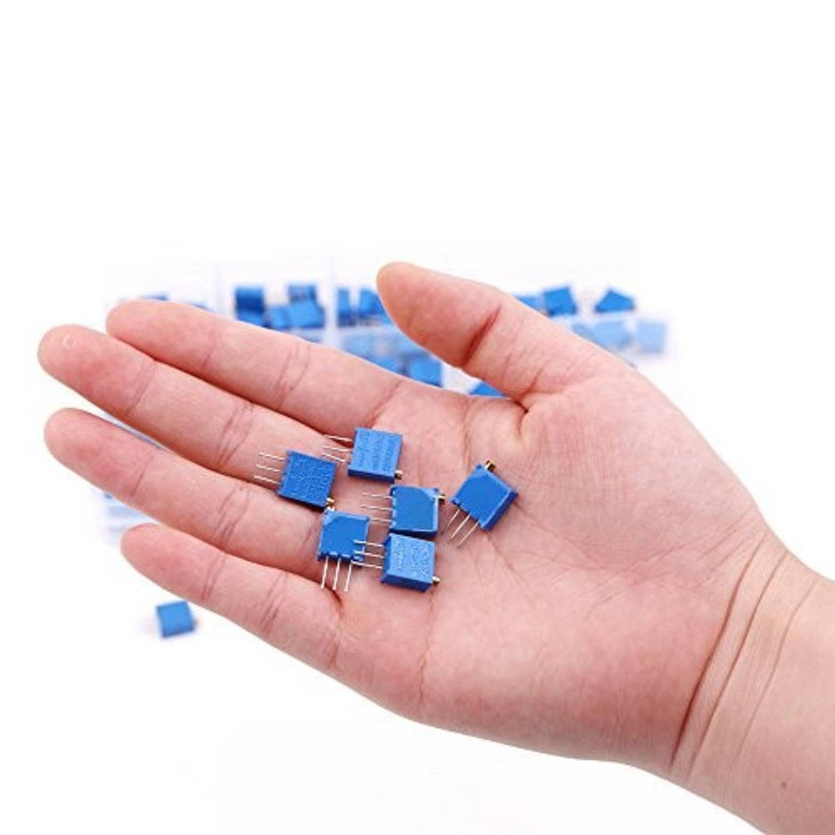 Hand holding several blue multiturn trimmer potentiometers with 3-pin leads