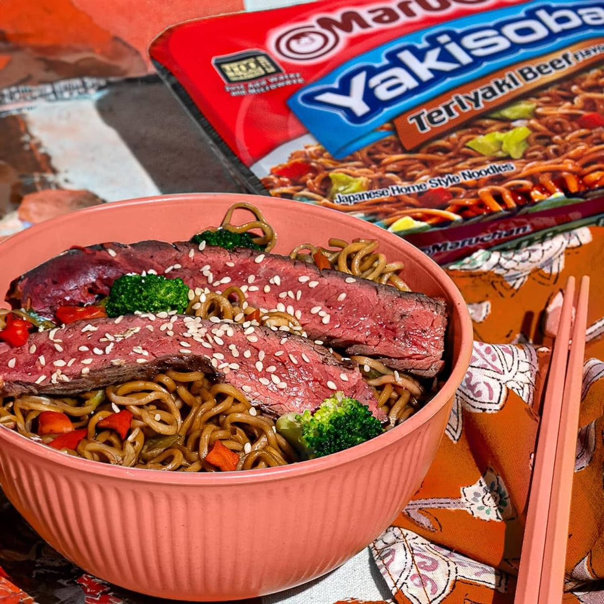 Bowl of yakisoba noodles topped with beef slices and sesame seeds