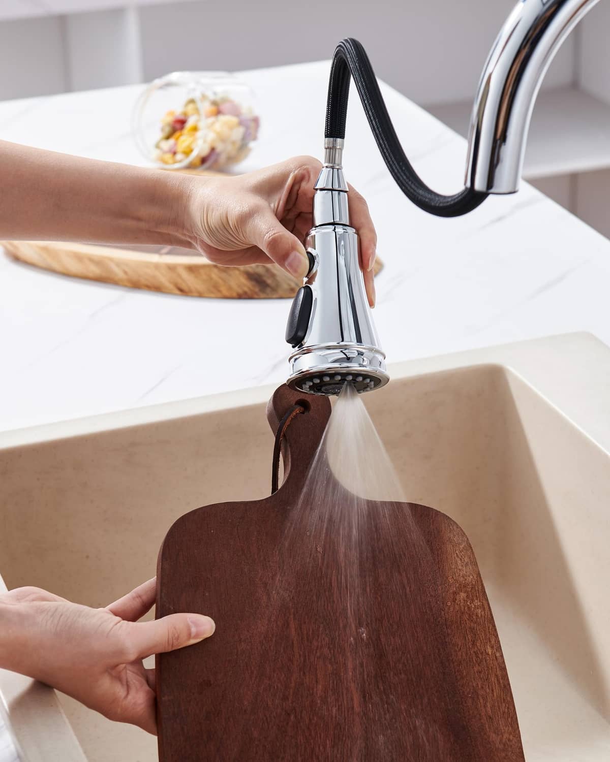 Chrome kitchen faucet spray head replacement being installed in a sink