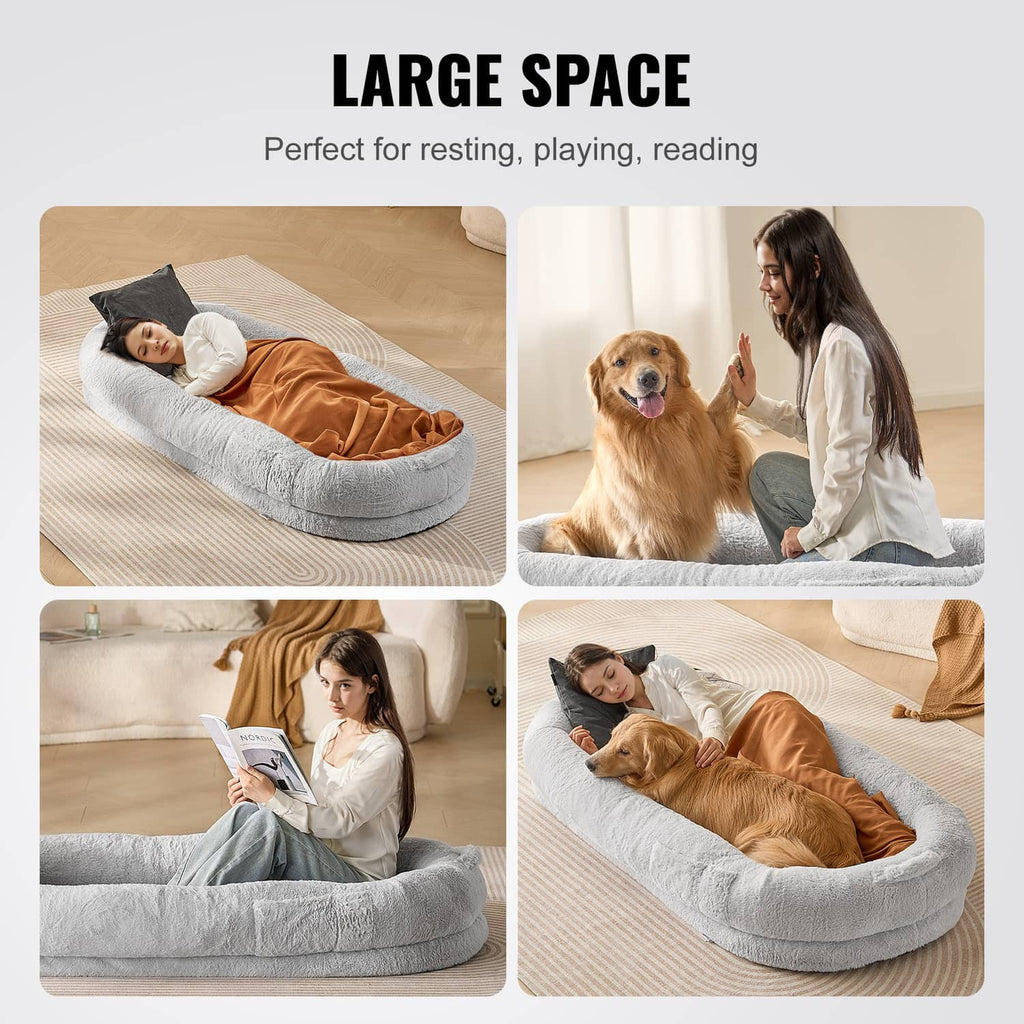 Grey oval human dog bed with plush sides, shown with person and dog resting.