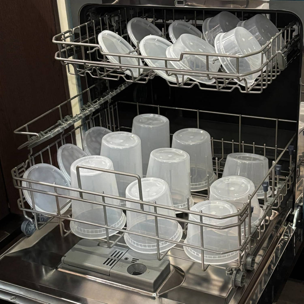 Clear plastic deli containers with lids in a dishwasher rack for cleaning