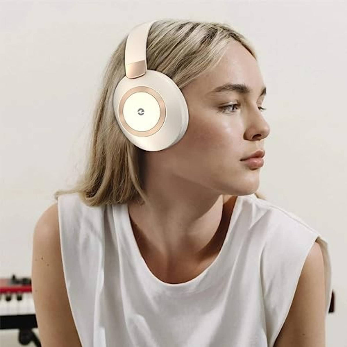 Beige wireless over-ear headphones worn over hair, round earcup controls visible