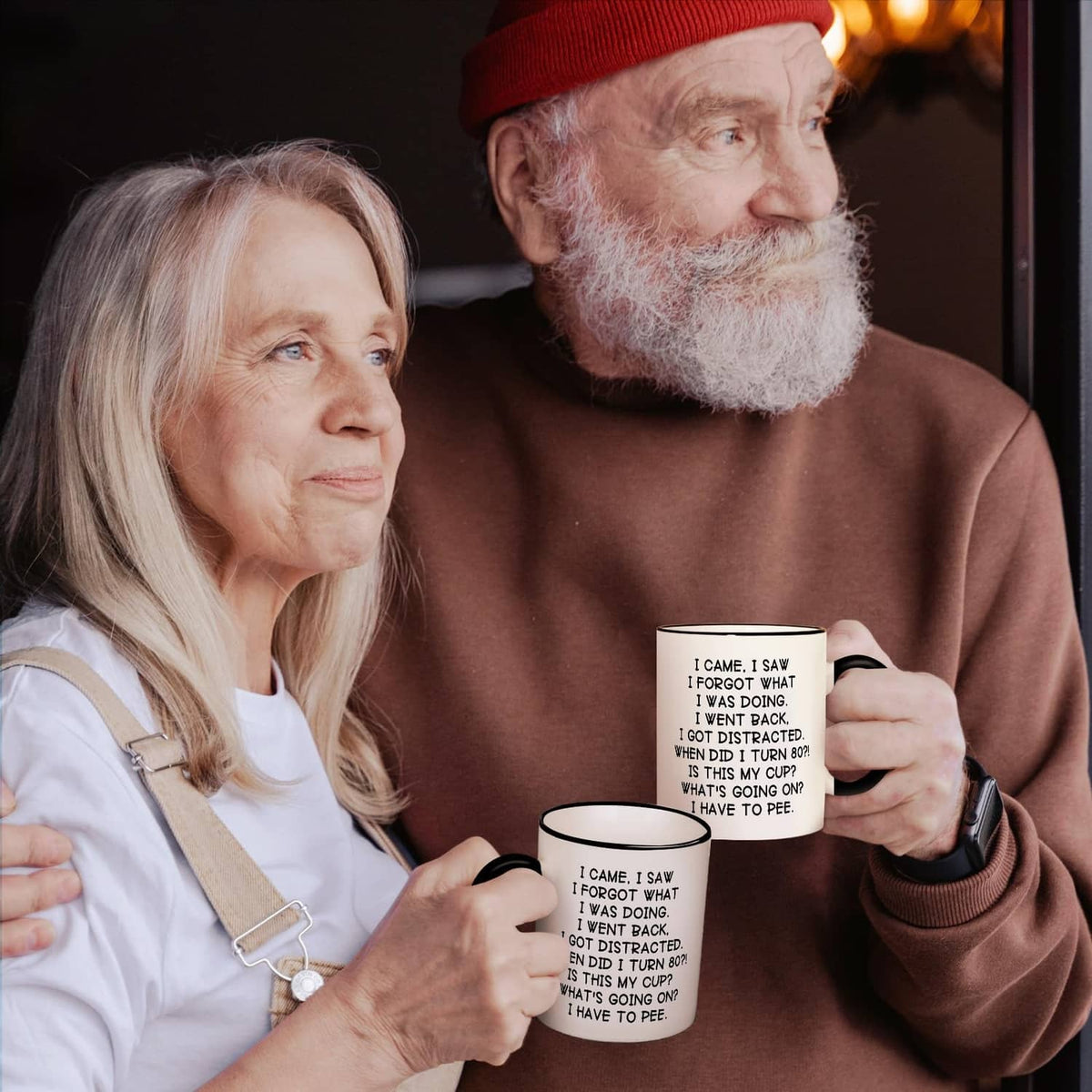 Two white mugs with black handles and rims, 'turn 80' quote, held in hands.