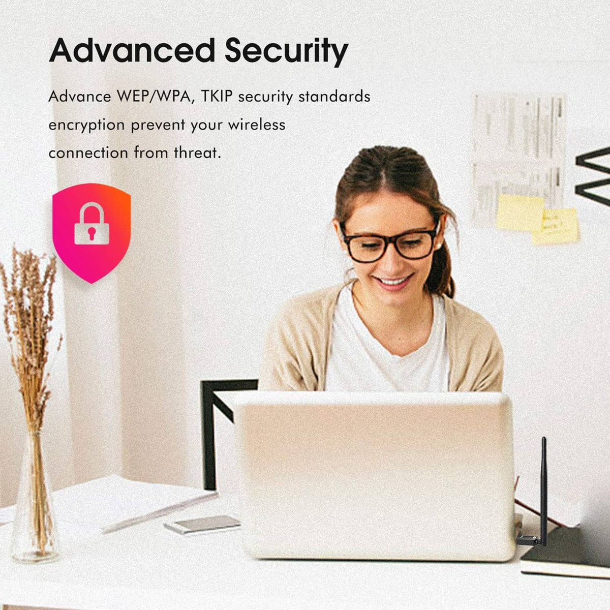 USB WiFi adapter with antenna placed beside a laptop on a desk