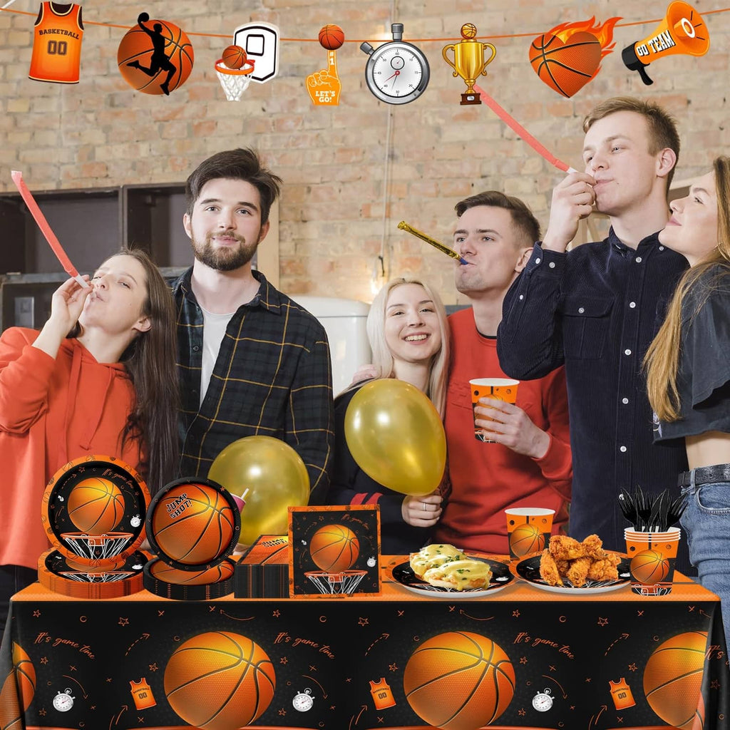 Basketball birthday party table set with cups and plates on black-orange patterned cloth