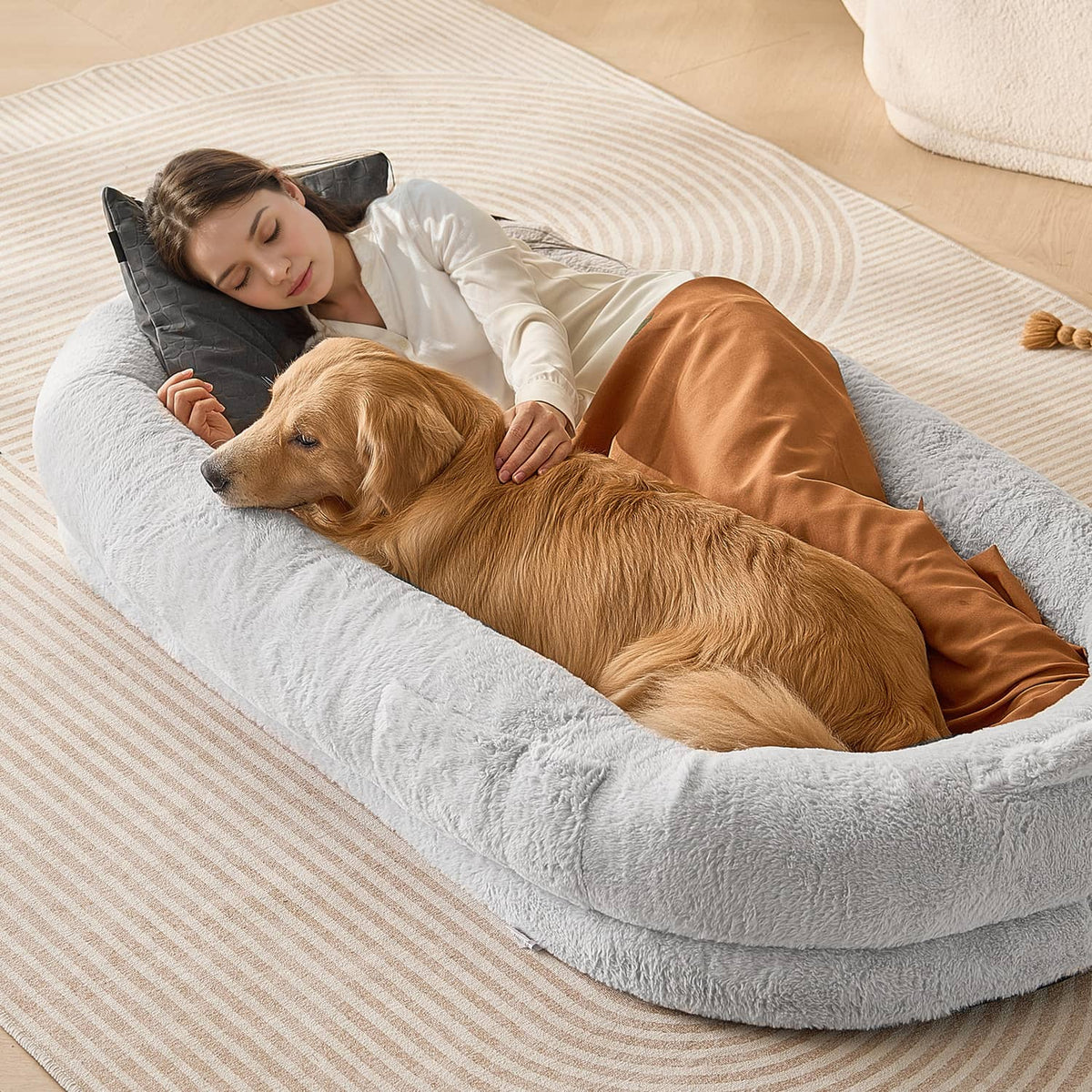 Grey oval dog bed with plush bolster, shown with golden dog lying inside.