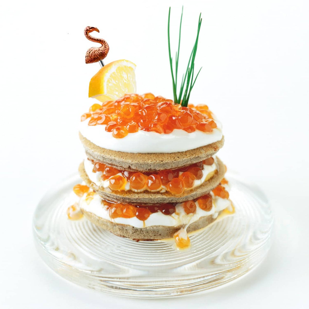 Flamingo cocktail pick in top of layered appetizer with citrus and herbs