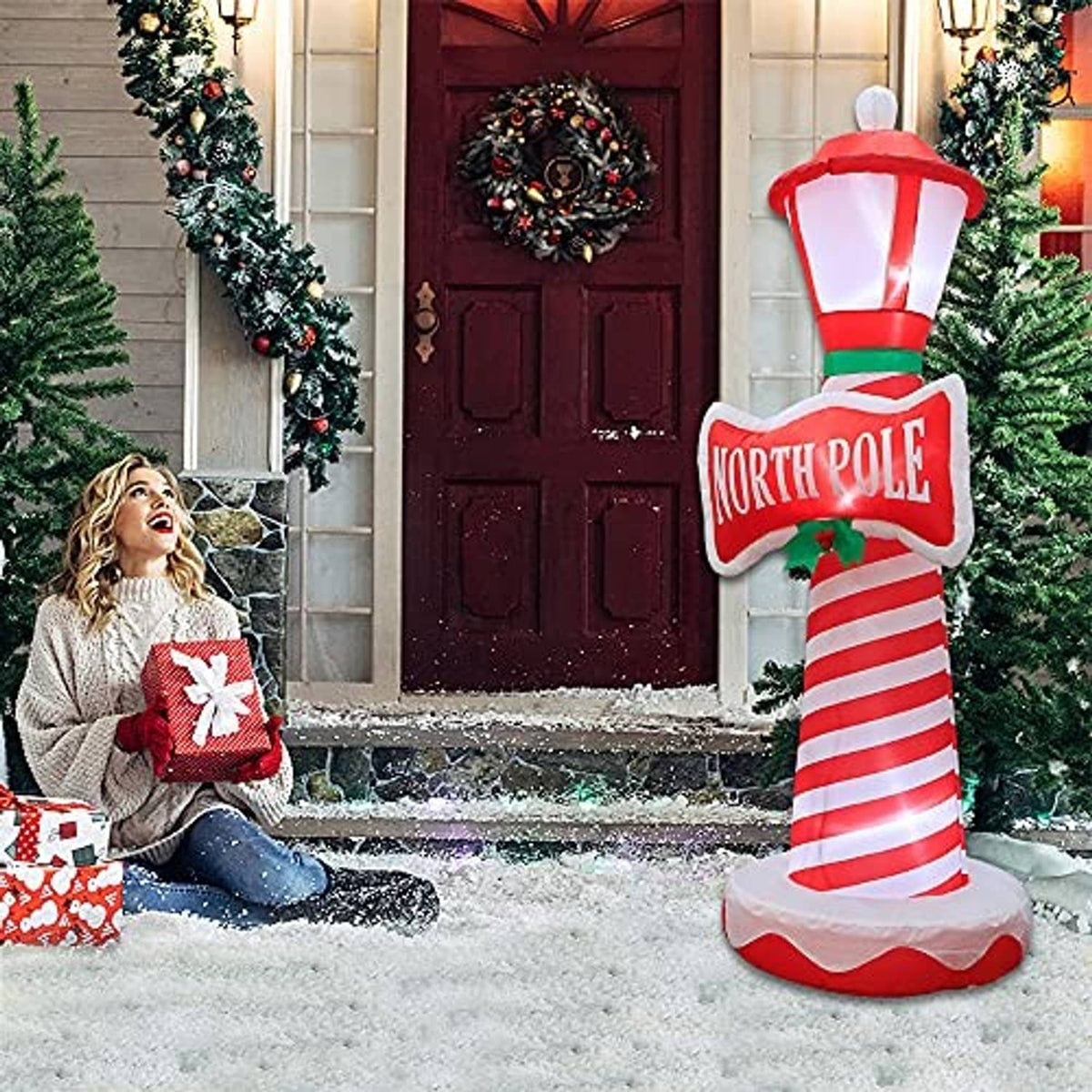 Inflatable lighthouse decoration by front door with glowing lantern, candy-cane stripes
