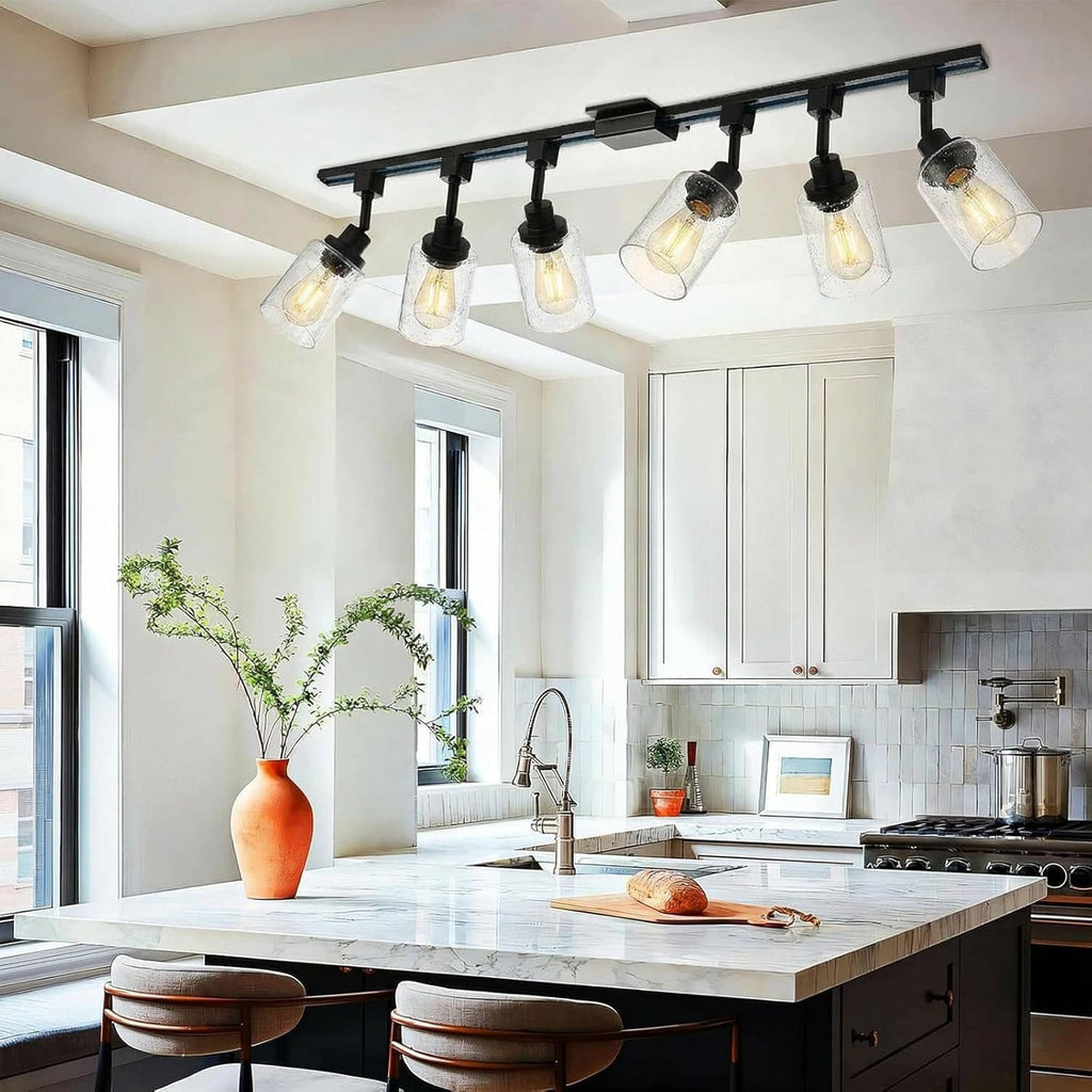 Ceiling track lighting with multiple black heads and seeded glass shades over kitchen island