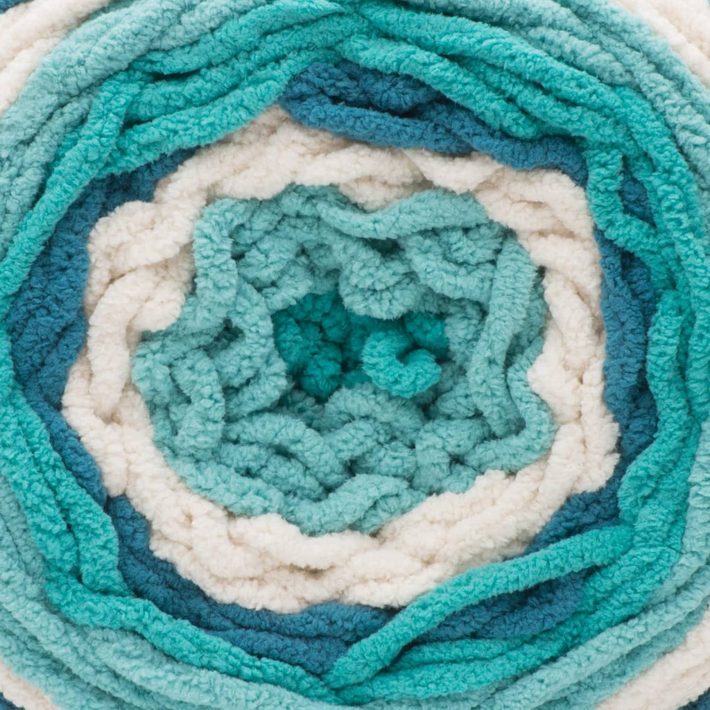 Close-up of teal and cream striped yarn blanket texture with rosette center.