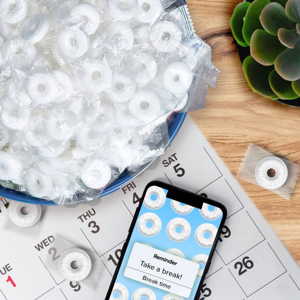 Pep O Mint mints in clear wrappers with calendar and phone on a wooden surface