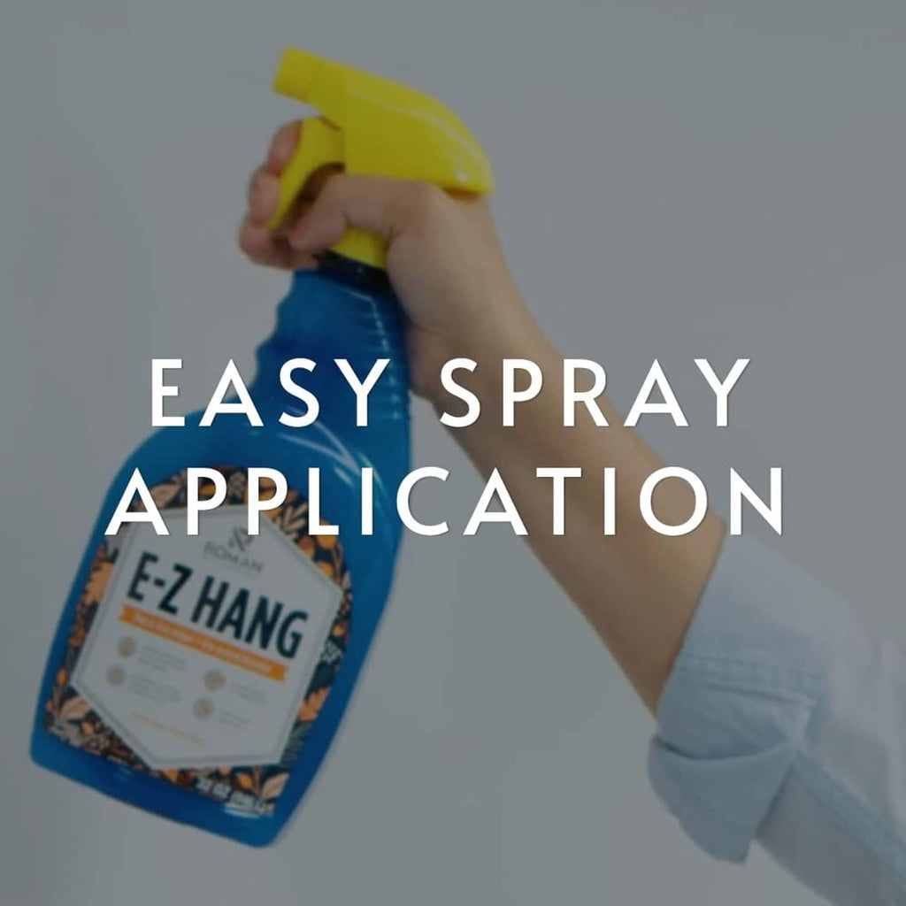 Hand holding blue E-Z Hang peel and stick wallpaper helper spray bottle