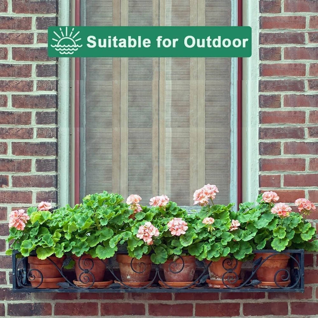 Terracotta plant pots with saucers lined along a brick wall planter