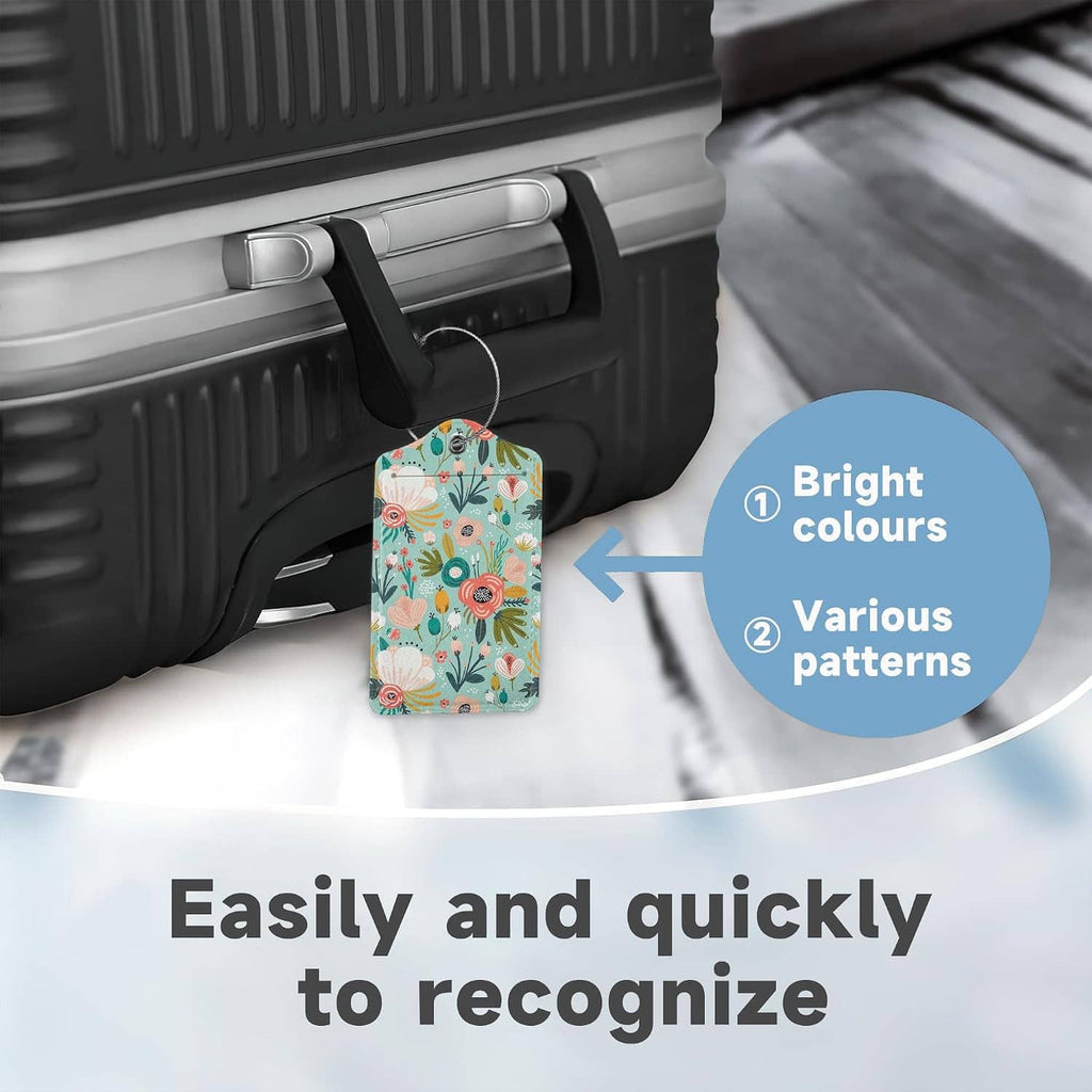 Floral luggage tag on a suitcase handle strap, teal tag with metal ring and cord