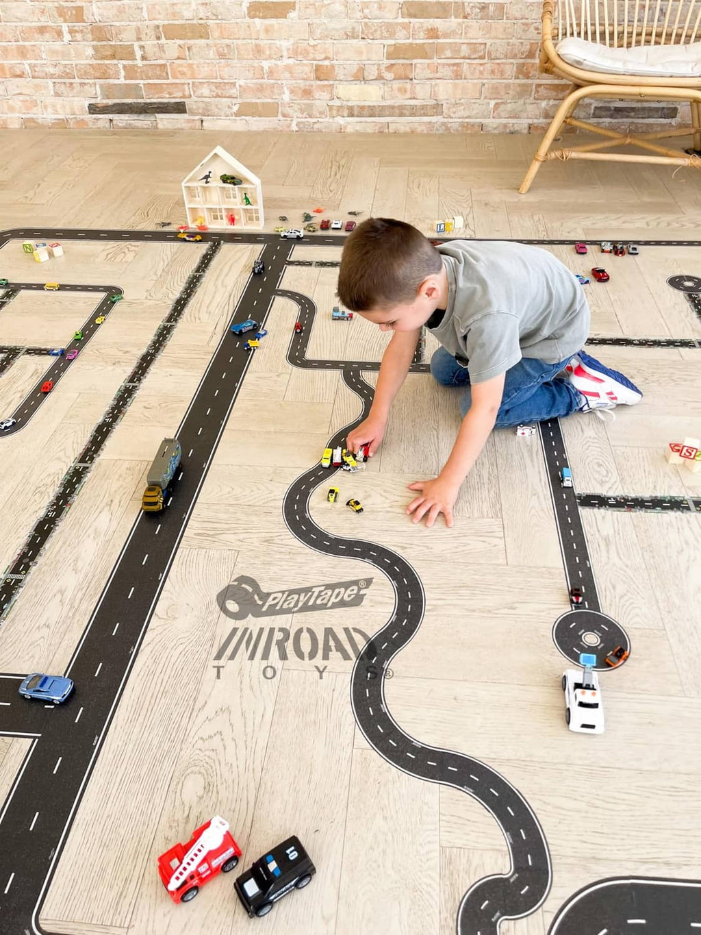 Toy road track tape on wood floor with black lanes and white markings, cars and vehicles included