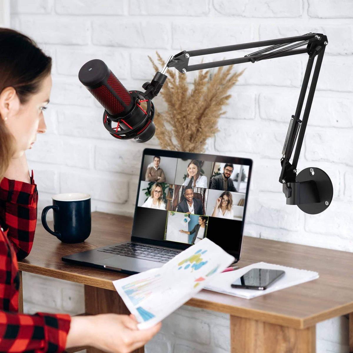 Black wall-mounted microphone boom arm holding a studio mic over a desk
