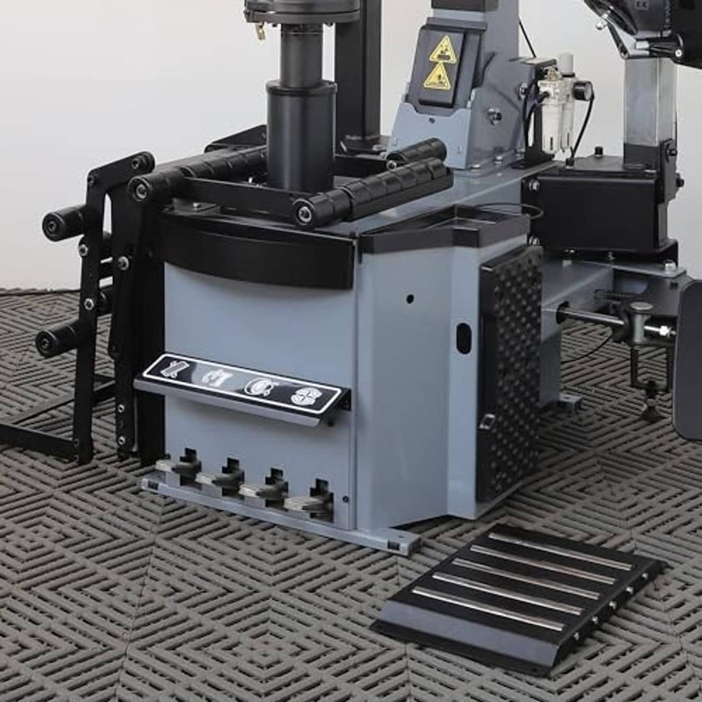 Tire changer base with black tool arm housing and slotted floor ramp