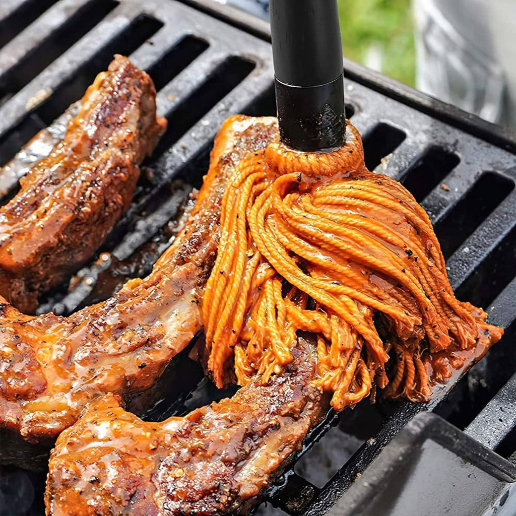 Grill basting mop spreading basting sauce on grilled meat on the grates