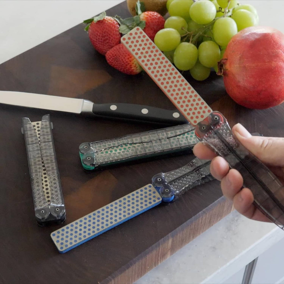 Portable sharpening stone with dotted pads and folding guide, hand holding the base