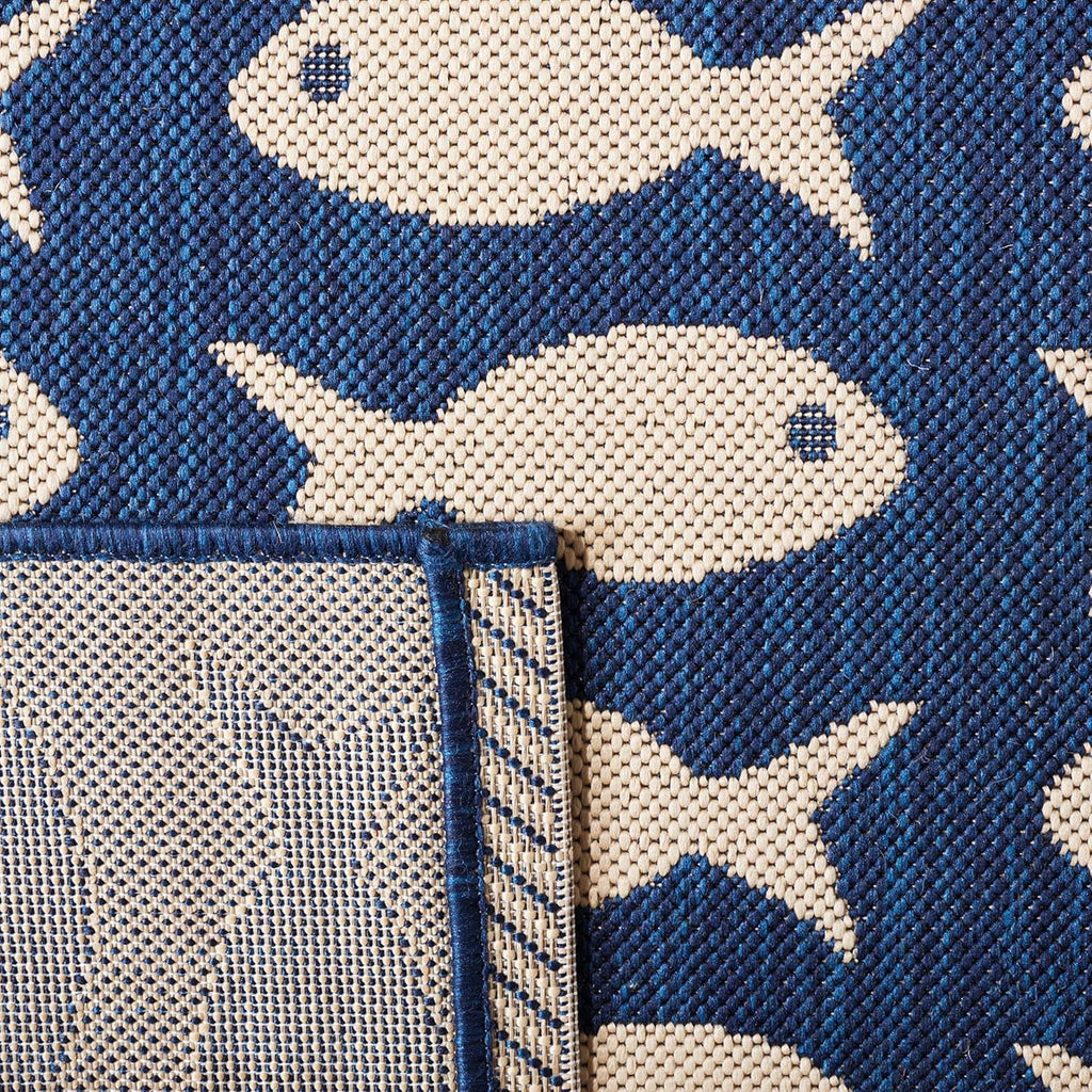 Close-up of navy and beige fish pattern rug edge with stitched trim.