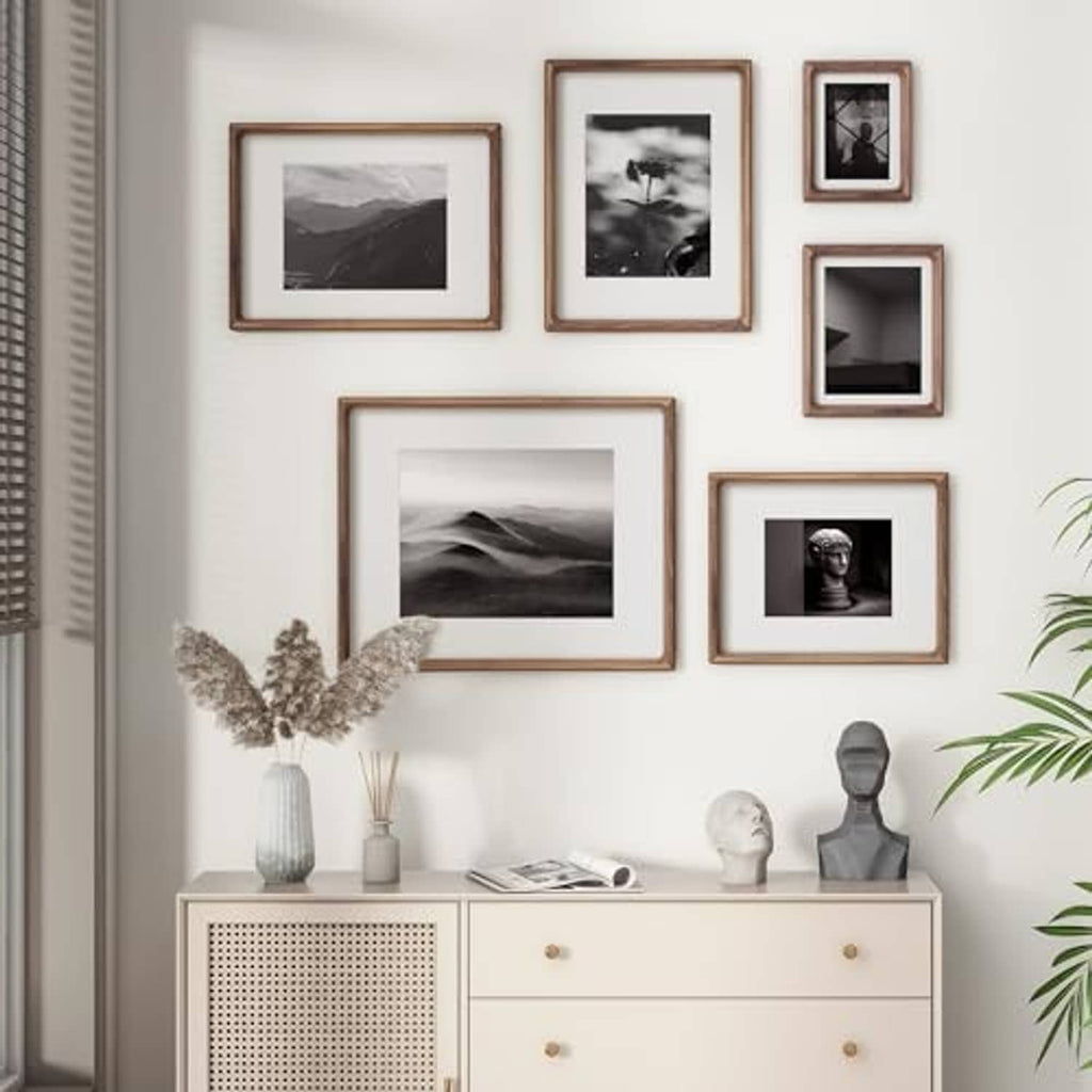 Wall gallery of walnut and dark wood picture frames with black-and-white photos