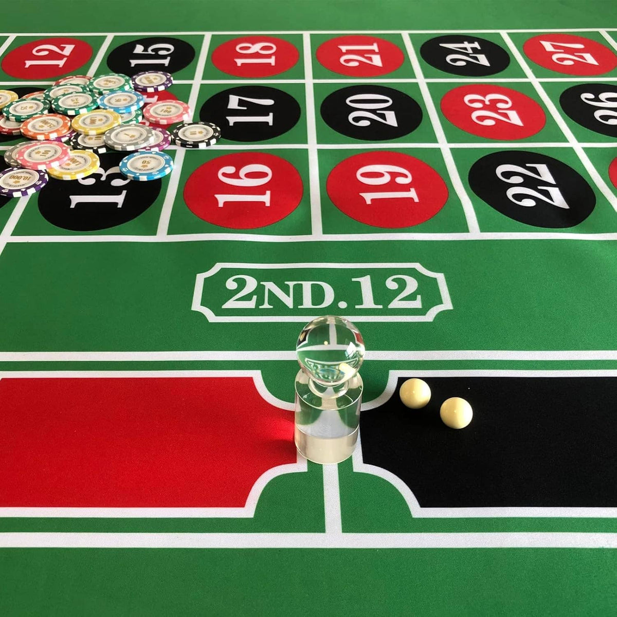 Acrylic roulette marker on green felt with two pale yellow balls on the table