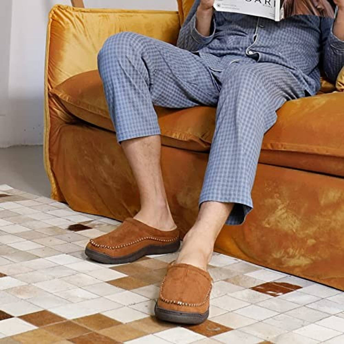 Tan suede slip-on moccasin slippers on feet with fuzzy interior lining