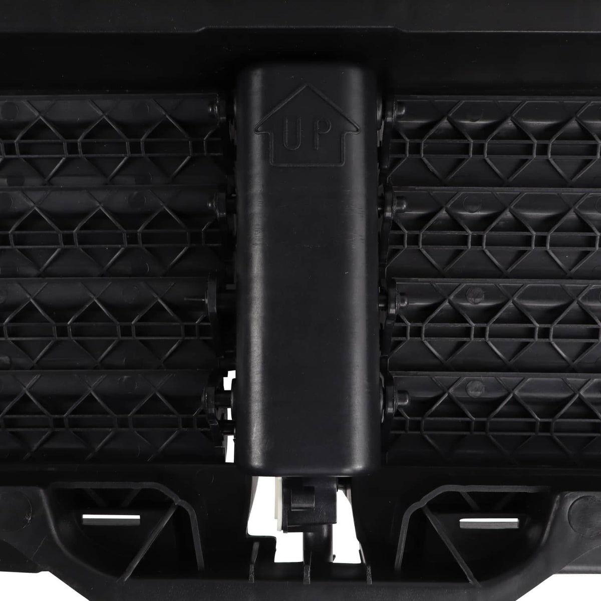 Close-up: black upper radiator grille air shutter actuator housing on slat grille