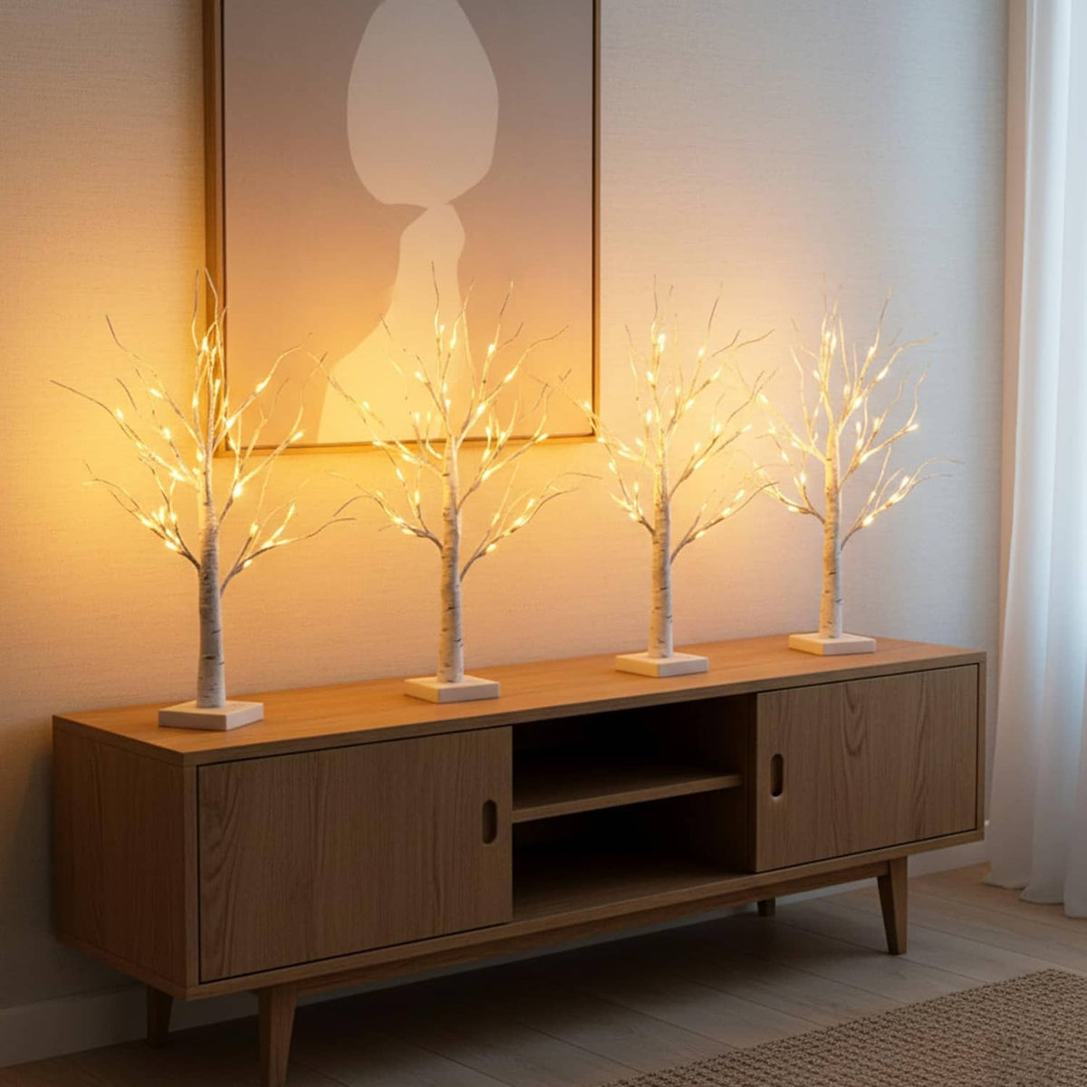 Three lighted birch tree decorations with white trunks and warm LEDs on console