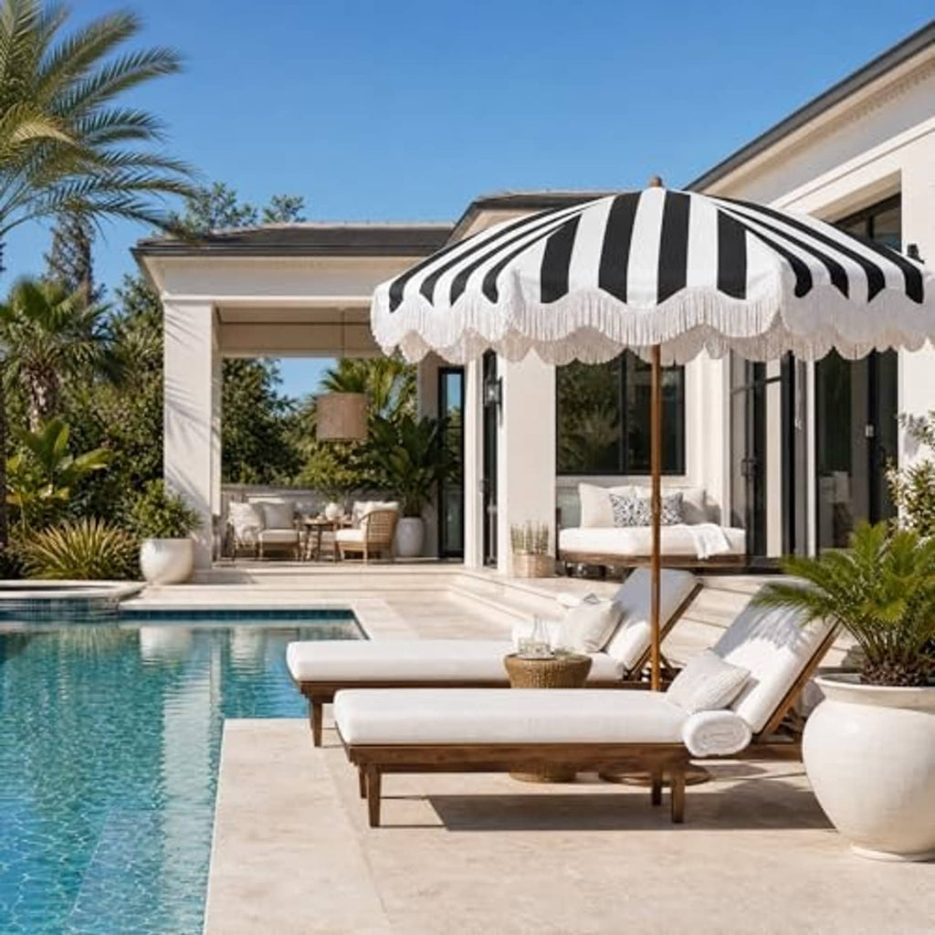 Black-and-white striped open patio umbrella with white tassel fringe and wooden pole