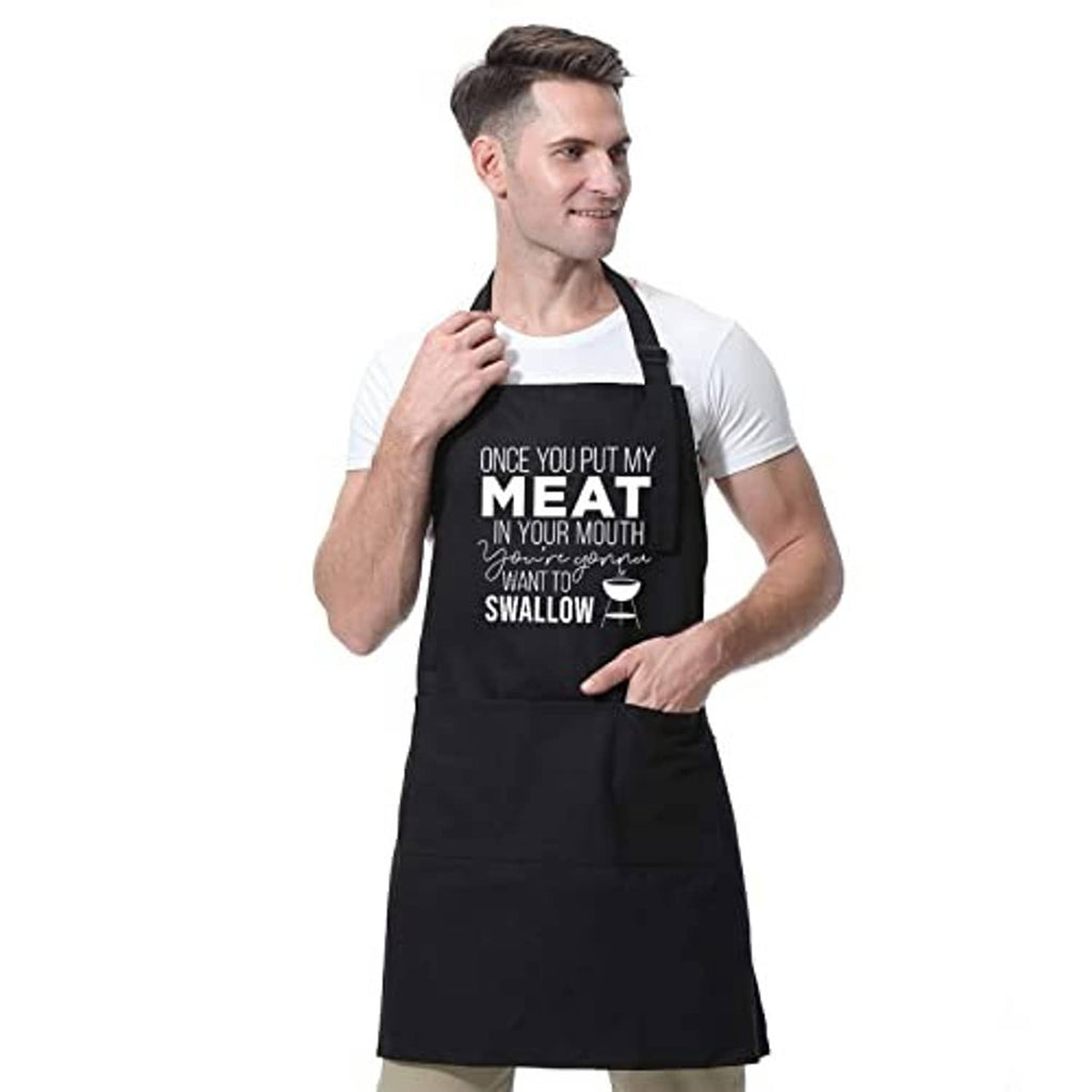 Black cooking apron worn by a man; centered "MEAT...SWALLOW" front graphic.