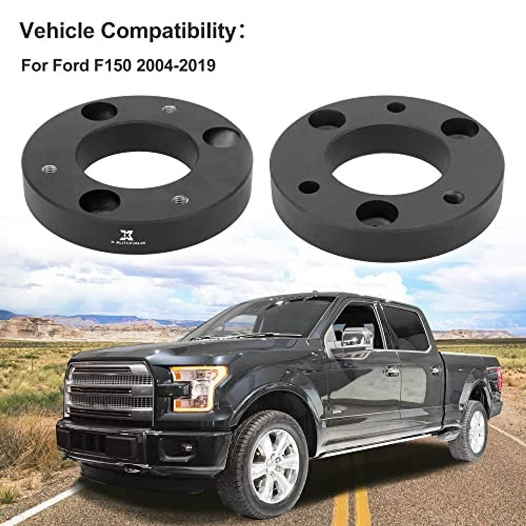 Two black front leveling lift spacers with bolt holes, shown with a pickup truck