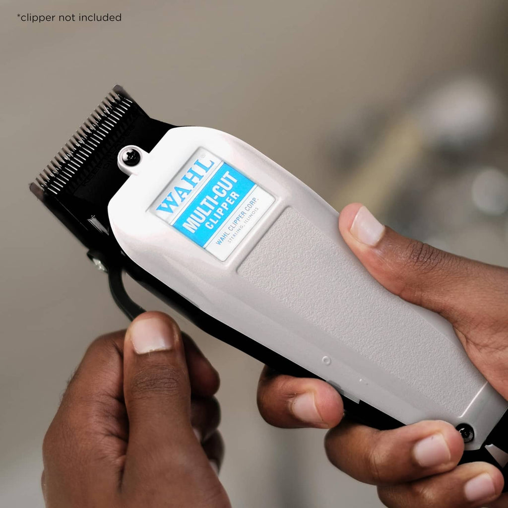 White-and-silver WAHL clipper held in hand with black cutting head