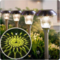 Solar pathway light set with stainless-steel stakes and frosted glass caps, glowing warm white.