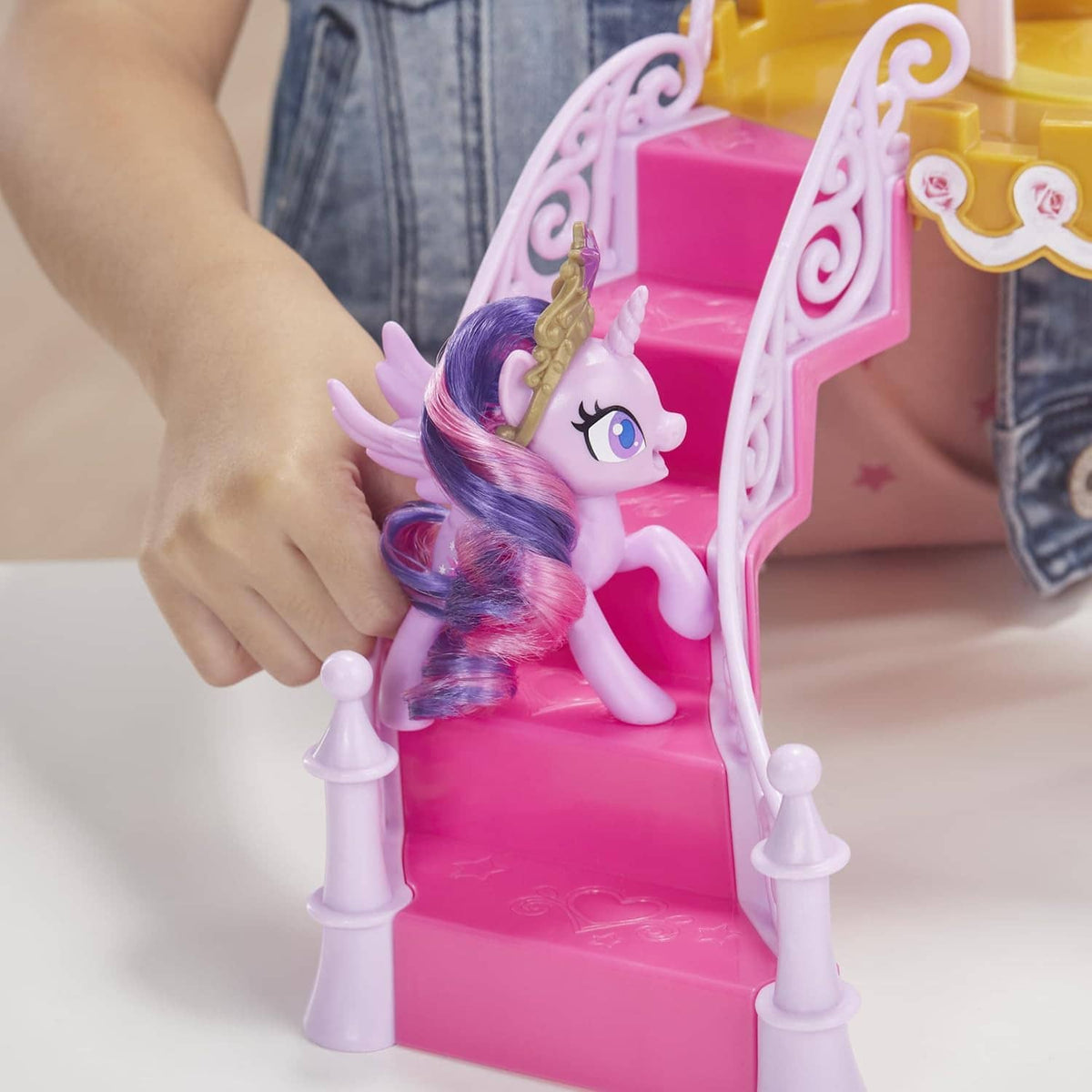 Pink pony figure on pink castle steps, with white fence details and gold trim