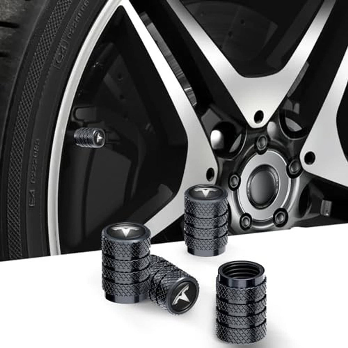 Black textured tire valve stem caps with V-emblem displayed on an alloy wheel