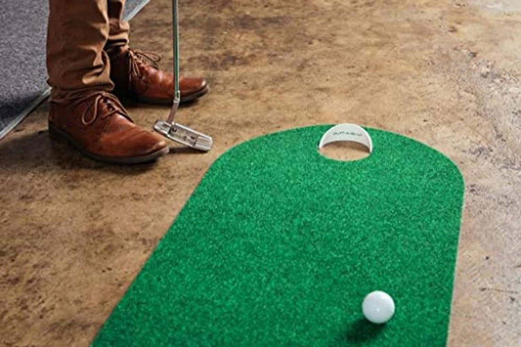 Green putting mat with hole area and white golf ball