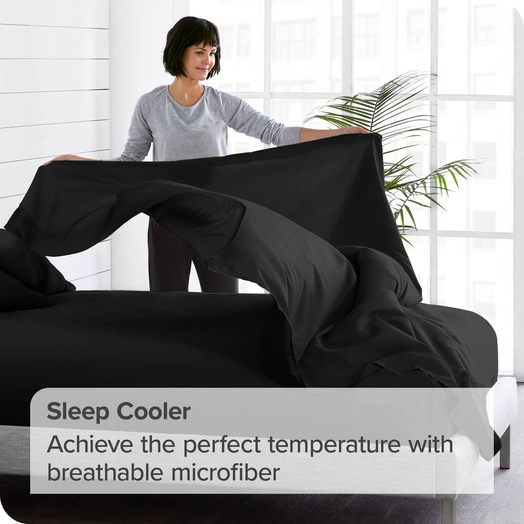 Black flat sheet draped over a bed with airy folds