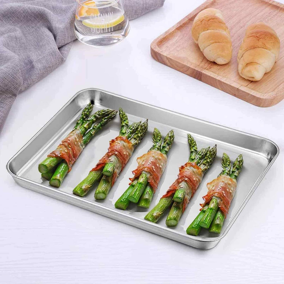 Stainless steel baking tray with roasted asparagus spears, rectangular shallow pan