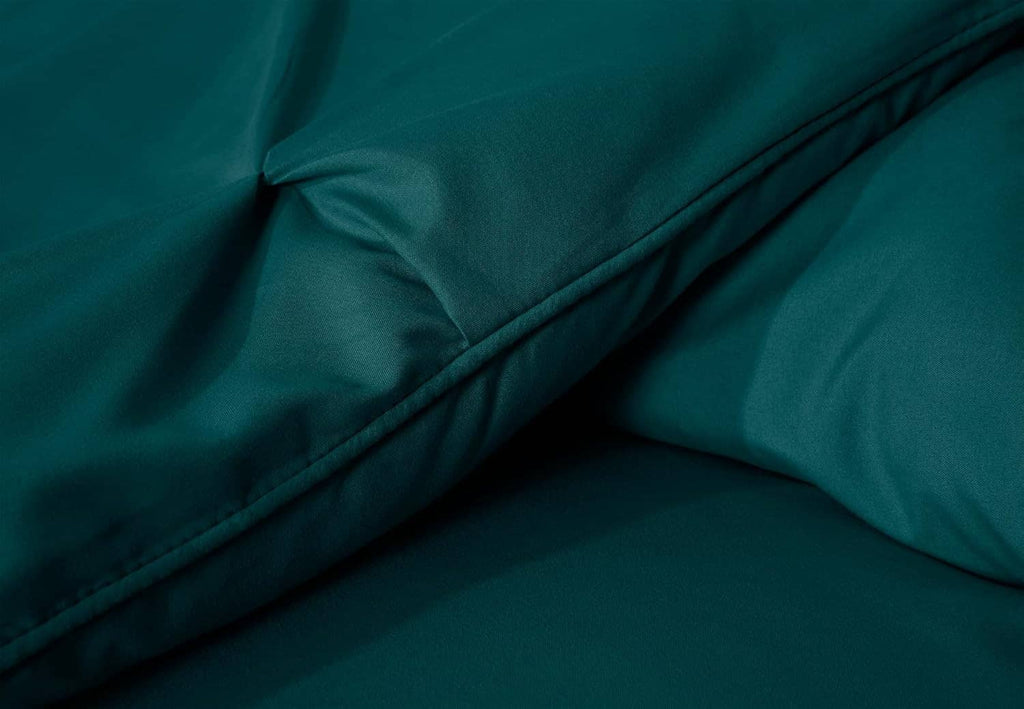 Teal comforter close-up showing stitched edge and smooth diamond tufting
