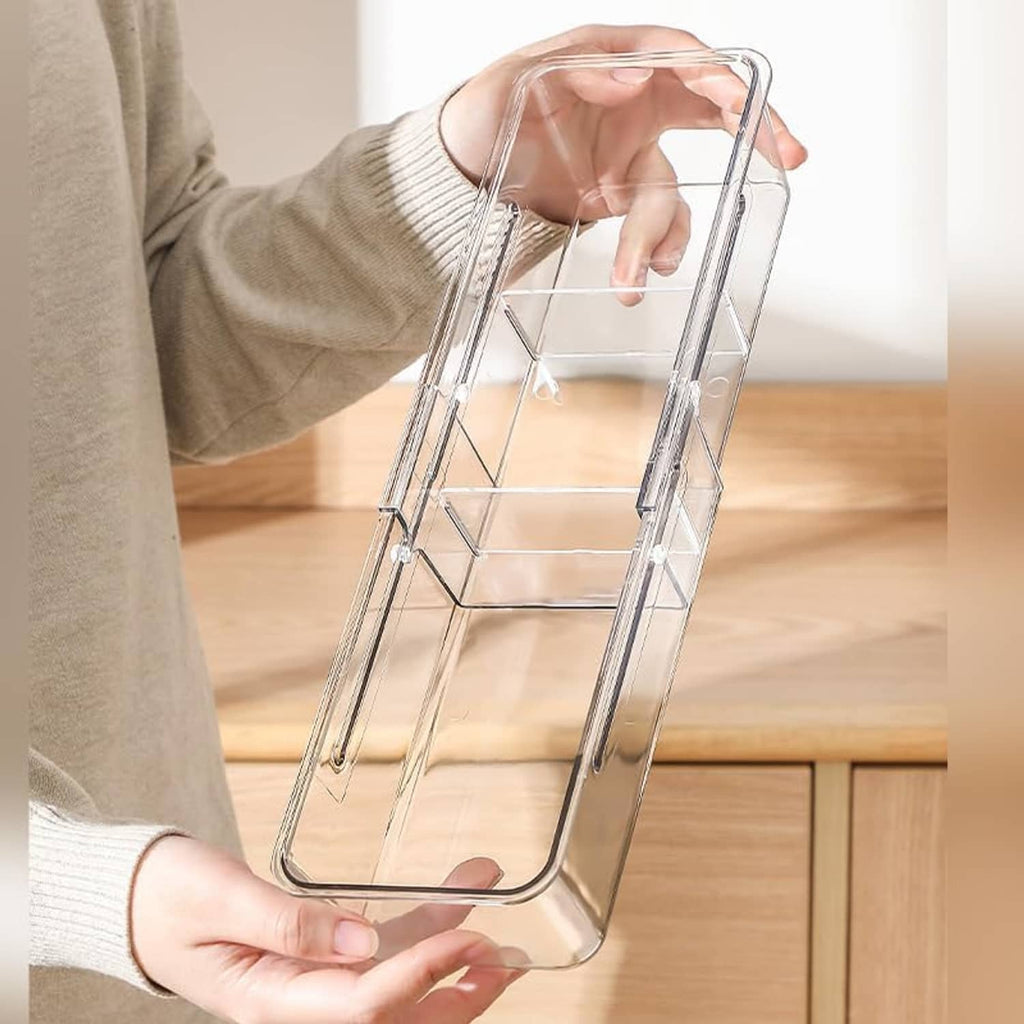 Hand holding a clear acrylic tea bag holder with open divider structure